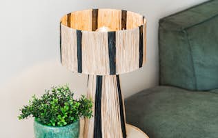 location - Sienna - Modern interior decoration with lamp and plant  location - Sienna - Image of a modern interior decoration featuring a stylish lamp and a potted plant on a table next to a green sofa.