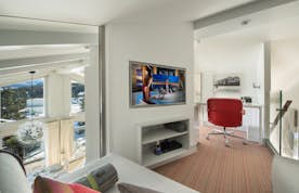 location - POW POW - Modern home office with panoramic view  location - POW POW - Elegant and modern home office with a stunning view of snow-capped mountains. The space is furnished with a red chair, flat screen TV, and designer furniture.