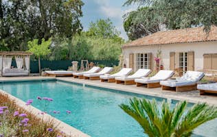location - Ferme des Salins - Luxury Home Pool and Terrace  location - Ferme des Salins - Image of an outdoor pool with lounge chairs and a luxury home in the background, surrounded by greenery.