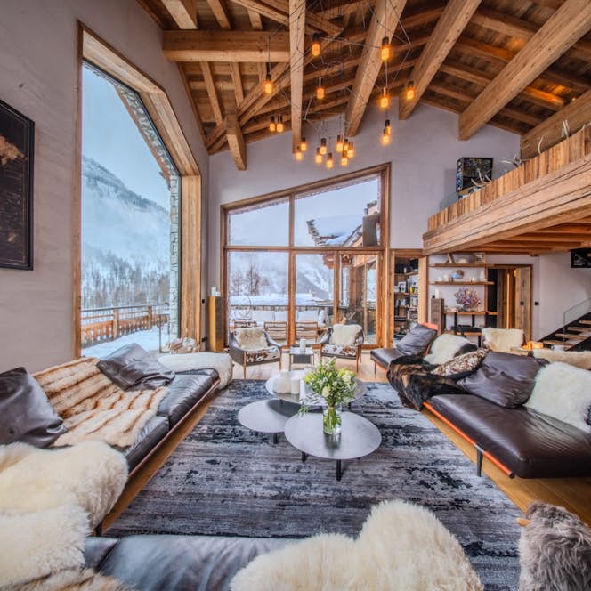 location - ORSO  - Modern living room with panoramic view  location - ORSO  - A modern living room with a panoramic view of snow-covered mountains. Decorated with leather sofas and fur rugs, this space is perfect for relaxing.
