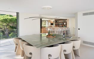 location - Casabianca - Modern dining room with garden view  location - Casabianca - This modern dining room features a green marble table with white chairs, offering a stunning view of the garden. The space is bright and airy, perfect for family or friendly gatherings.