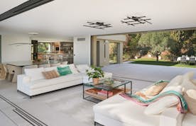 location - Casabianca - Modern living room with garden view  location - Casabianca - This image shows a modern living room with an elegant design and a stunning view of the garden. The room is furnished with white sofas and contemporary furniture, creating a warm and inviting atmosphere.