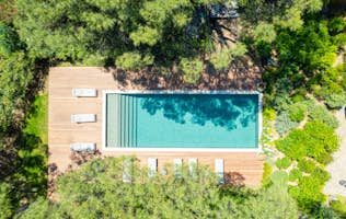 location - Serena - Modern pool with wooden deck  location - Serena - This image shows a modern rectangular pool surrounded by a wooden deck. The area is surrounded by lush greenery, providing a natural and serene setting.