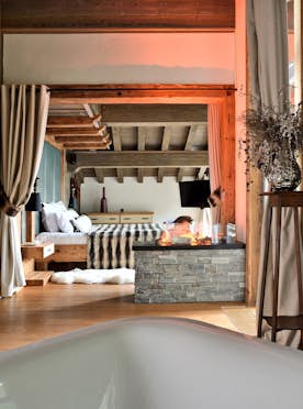 accommodation - Labaobou - Luxurious Room with Bathtub and Fireplace  accommodation - Labaobou - This luxurious room features a modern bathtub, stone fireplace, and a comfortable bed. The warm ambiance is enhanced by wooden elements and elegant curtains.