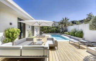 location - Marguerite - Modern pool and patio with outdoor furniture  location - Marguerite - This image shows a modern pool surrounded by a wooden patio with outdoor furniture. The space is perfect for relaxing and enjoying the good weather.