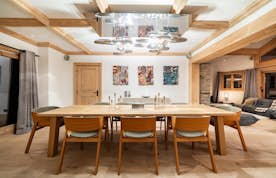 location - Les Arolles  - Modern dining room with artistic decoration  location - Les Arolles  - This modern dining room features a wooden table surrounded by designer chairs. The artistic wall decoration and unique chandelier add a touch of elegance to the space.