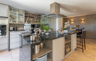 location - Suspiro - Modern and well-equipped kitchen  location - Suspiro - This modern and well-equipped kitchen features glass cabinets, high-end appliances, and a large central island with stools. Perfect for cooking enthusiasts.