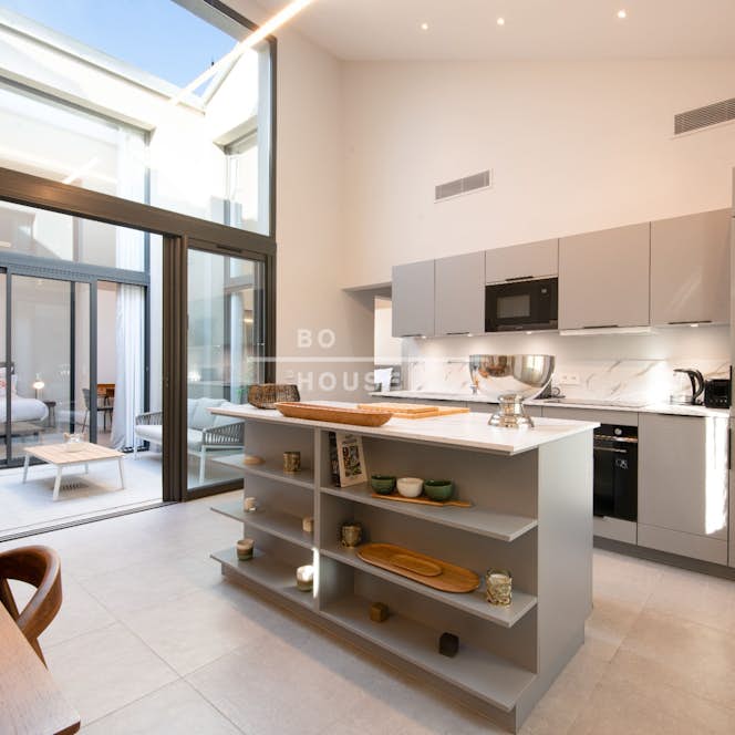 location - Juma - Modern kitchen with central island  location - Juma - This modern kitchen features an elegant design with a central island, white cabinets, and high-quality appliances. The space is bright and airy thanks to the large windows.