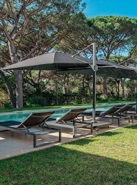 location - Les Lices - Pool with lounge chairs and umbrellas  location - Les Lices - Image of an outdoor pool surrounded by lounge chairs and umbrellas, offering an ideal relaxation setting.