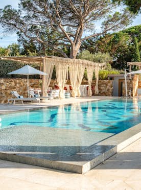 location - Canoubwest - Outdoor Pool with Pergola and Lounge Chairs  location - Canoubwest - This image shows a beautiful outdoor pool with a pergola, lounge chairs, and umbrellas, surrounded by a natural and serene setting.