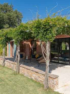 location - Beausoleil - Modern outdoor terrace with pergola  location - Beausoleil - This image shows a modern outdoor terrace with a wooden pergola, providing a relaxing space. The house has a terracotta facade and a well-maintained garden.