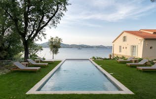 location - Ancre - Pool with lake view  location - Ancre - Beautiful outdoor pool with a stunning view of the lake, surrounded by lounge chairs and a beautiful natural landscape.