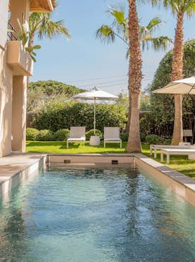 location - Noria - Modern outdoor pool with deck and palm trees  location - Noria - This image shows a modern outdoor pool surrounded by a wooden deck and palm trees. The space is perfect for relaxation and outdoor activities.