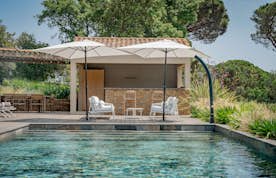 location - Marco Polo - Pool with deck and cabin  location - Marco Polo - Image of an outdoor pool with a wooden deck, a cabin, and lounge chairs, surrounded by lush greenery.
