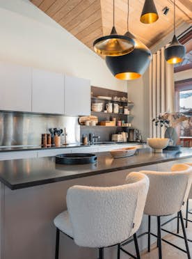 accommodation - Arpont  - Modern kitchen with island  accommodation - Arpont  - This modern kitchen features an island with stools, built-in appliances, and a view of a wooden building.