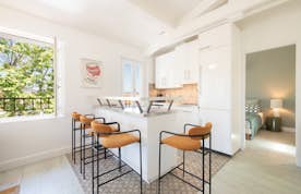 location - Riviera - Modern kitchen with central island  location - Riviera - This modern kitchen features a central island with stools, white cabinets, and elegant decor. Perfect for contemporary design enthusiasts.